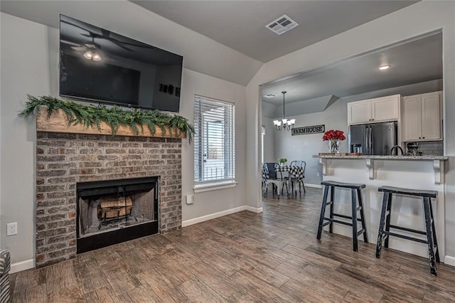 kitchen with visible vents, white cabinets, a breakfast bar area, a fireplace, and refrigerator with ice dispenser