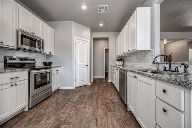 kitchen featuring stainless steel appliances, a sink, visible vents, white cabinets, and dark wood-style floors