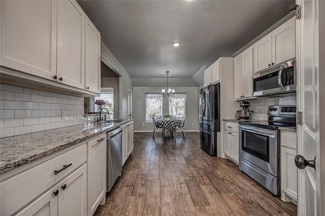 kitchen with a notable chandelier, dark wood-style flooring, a sink, white cabinets, and appliances with stainless steel finishes