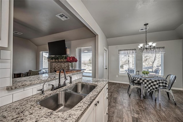 kitchen with visible vents, dark wood-type flooring, white cabinets, vaulted ceiling, and a sink