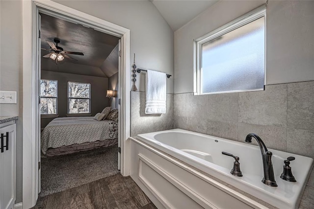 bathroom featuring a garden tub, lofted ceiling, ceiling fan, connected bathroom, and wood finished floors