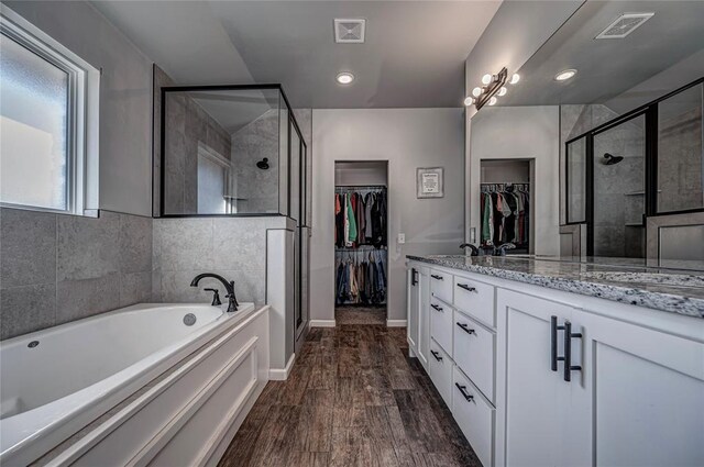 full bath featuring a spacious closet, a stall shower, wood finished floors, and visible vents