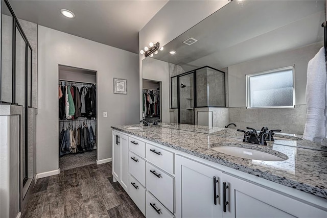 full bathroom featuring wood finished floors, a sink, a shower stall, and a spacious closet