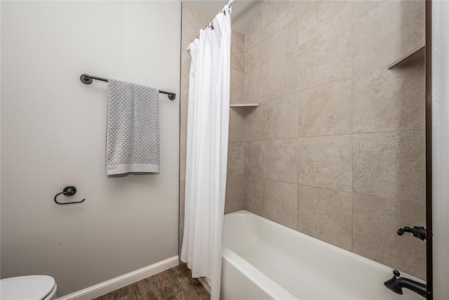 full bathroom featuring shower / tub combo, wood finished floors, toilet, and baseboards