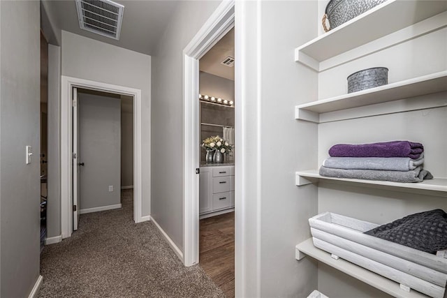 interior space featuring baseboards, visible vents, and dark carpet