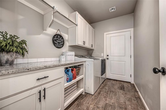 laundry room with visible vents, baseboards, washer and dryer, cabinet space, and dark wood finished floors