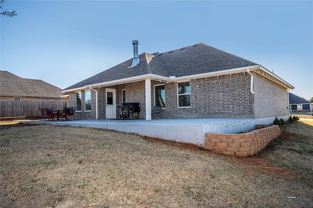 rear view of house featuring a patio area, fence, a lawn, and brick siding