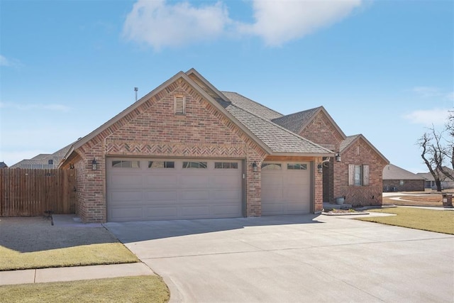 view of front of house with driveway, brick siding, an attached garage, and fence