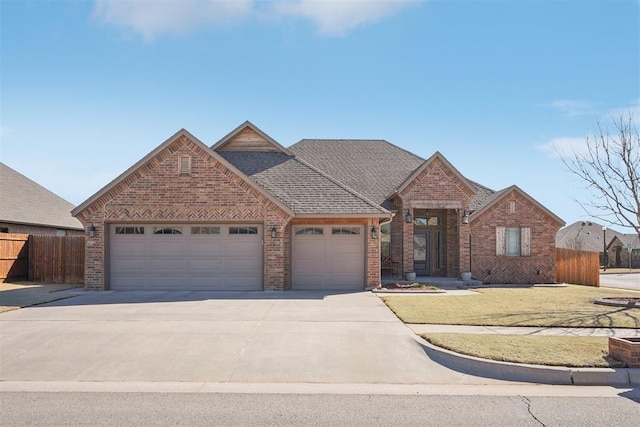 traditional-style house featuring driveway, brick siding, an attached garage, and fence