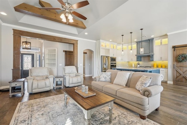 living area with arched walkways, dark wood finished floors, and crown molding