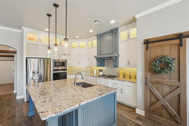 kitchen featuring visible vents, arched walkways, appliances with stainless steel finishes, a sink, and backsplash