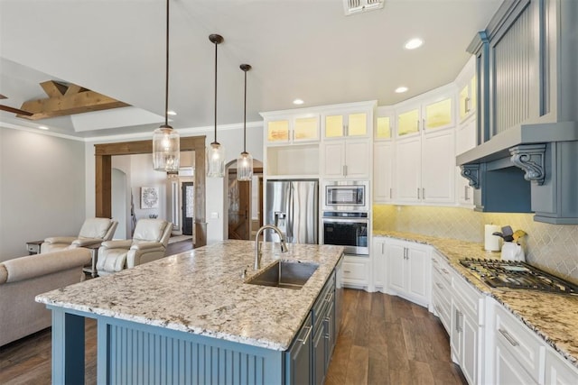 kitchen with appliances with stainless steel finishes, open floor plan, a sink, and tasteful backsplash