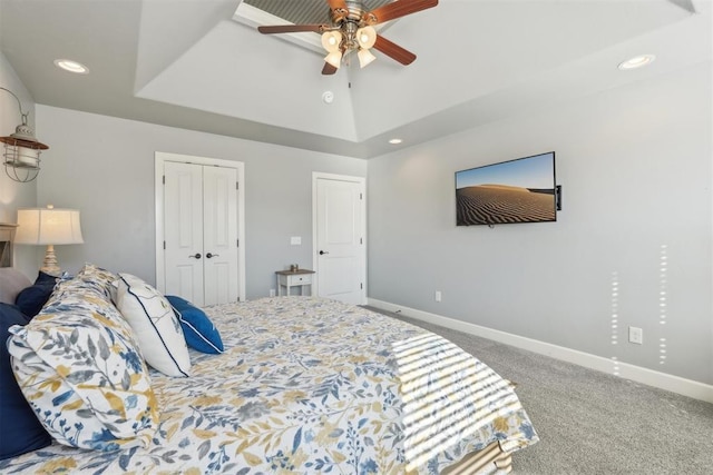 carpeted bedroom with a closet, recessed lighting, a raised ceiling, and baseboards