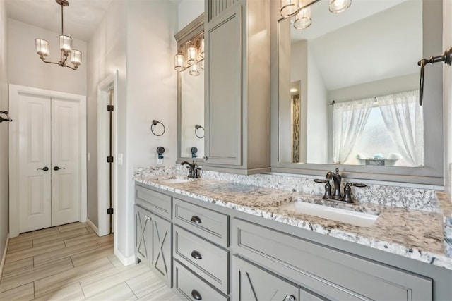 full bathroom featuring double vanity, a chandelier, a sink, and wood finish floors