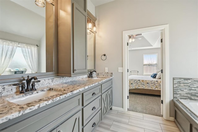 bathroom featuring double vanity, a bathing tub, a sink, and ensuite bathroom