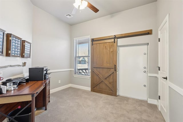 office area with light colored carpet, visible vents, a barn door, a ceiling fan, and baseboards