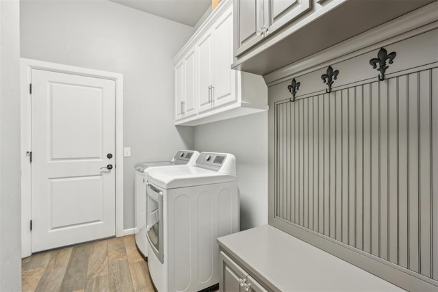 washroom with light wood finished floors, washer and clothes dryer, and cabinet space