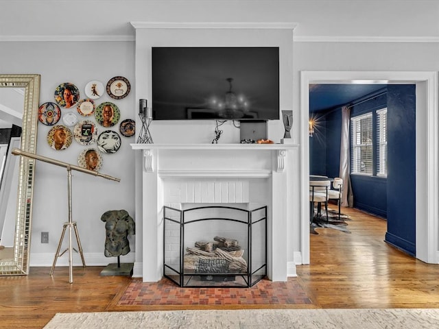 living room featuring ornamental molding, a brick fireplace, wood finished floors, and baseboards