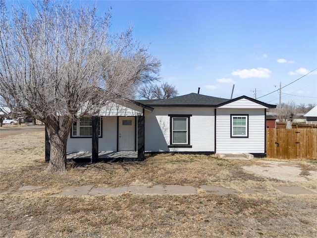 ranch-style home with a shingled roof, fence, and brick siding