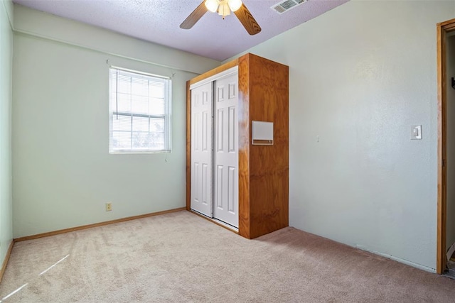 unfurnished bedroom with a textured ceiling, a closet, carpet, and visible vents