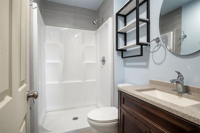 bathroom with a stall shower, a textured wall, vanity, and toilet