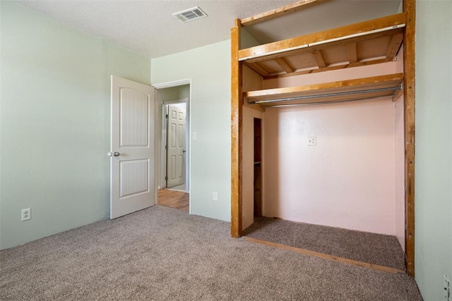 unfurnished bedroom featuring carpet, visible vents, and a textured ceiling