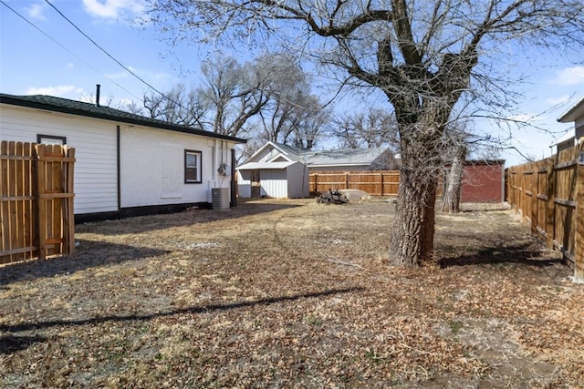 view of yard featuring a fenced backyard, a storage unit, and an outdoor structure