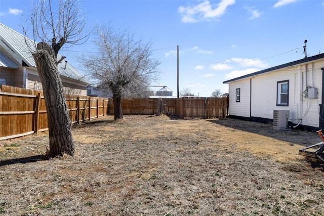 view of yard with a fenced backyard and central AC unit