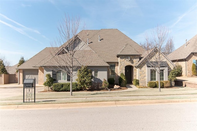 view of front of home featuring an attached garage, a shingled roof, fence, driveway, and stone siding