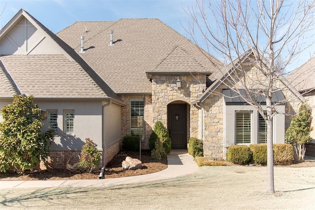 view of front of home with stone siding, a shingled roof, and stucco siding