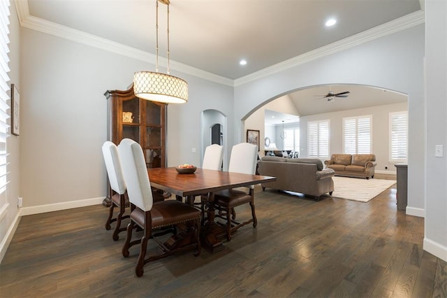 dining area featuring baseboards, arched walkways, dark wood-style flooring, and ornamental molding