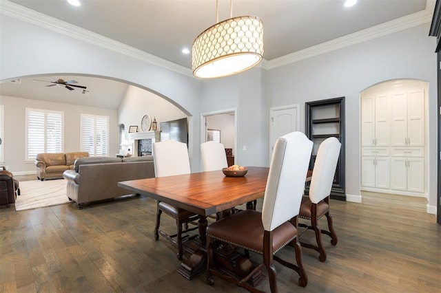 dining area featuring baseboards, crown molding, arched walkways, and dark wood-style flooring