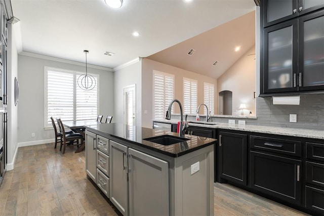 kitchen with tasteful backsplash, crown molding, a sink, and dark stone countertops