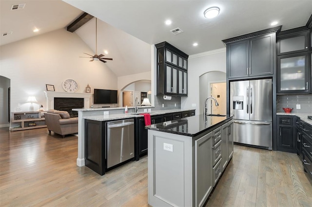 kitchen featuring appliances with stainless steel finishes, visible vents, light wood-style flooring, and dark stone countertops