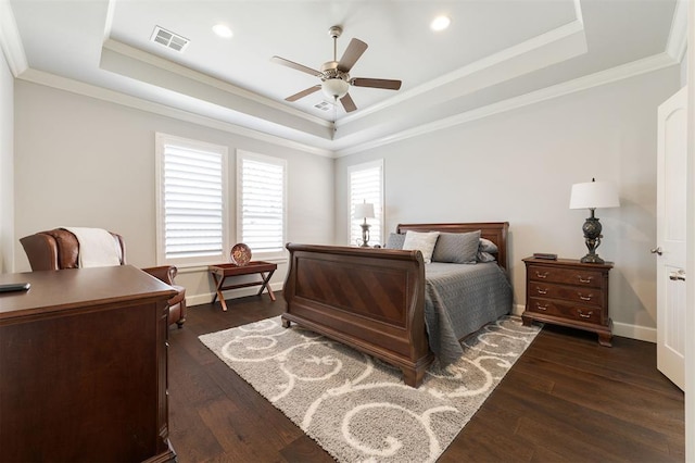 bedroom with a tray ceiling, dark wood finished floors, visible vents, and crown molding