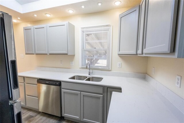 kitchen with appliances with stainless steel finishes, gray cabinets, light countertops, and a sink