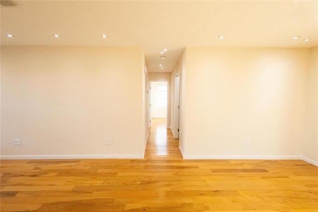 empty room with baseboards, light wood finished floors, and recessed lighting