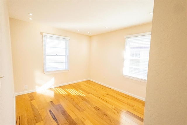 spare room with plenty of natural light, wood finished floors, and baseboards