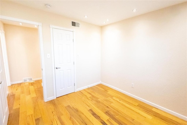 empty room featuring light wood-type flooring, visible vents, and baseboards