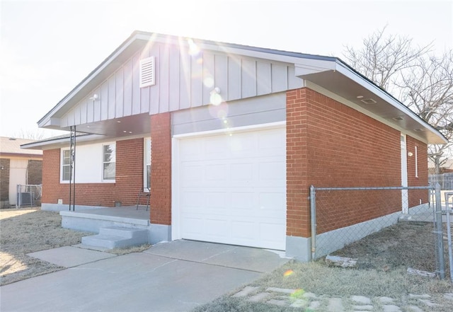 view of property exterior featuring a garage, brick siding, fence, concrete driveway, and board and batten siding