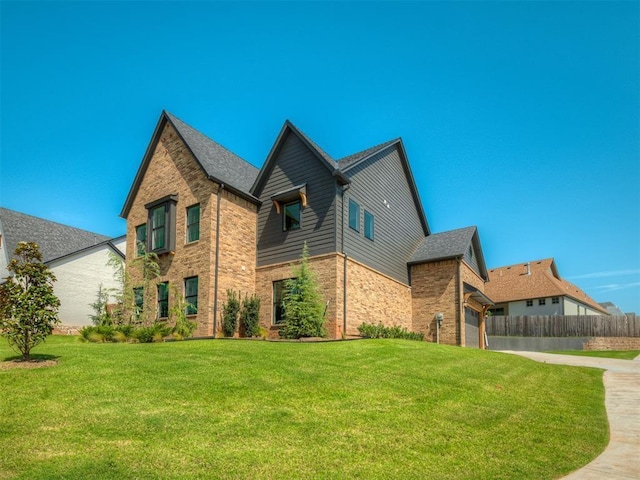 view of property exterior featuring a yard, brick siding, driveway, and fence