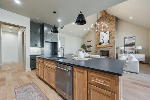 kitchen featuring dark countertops, light wood-style floors, a sink, and an island with sink