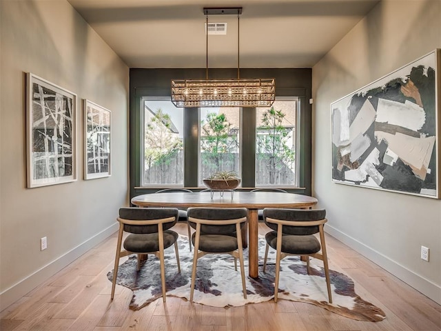 dining room with a healthy amount of sunlight, light wood-style floors, baseboards, and visible vents