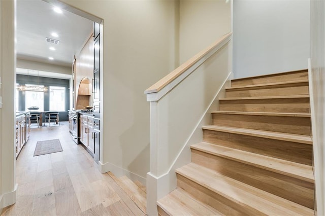 stairs with wood finished floors, visible vents, and recessed lighting