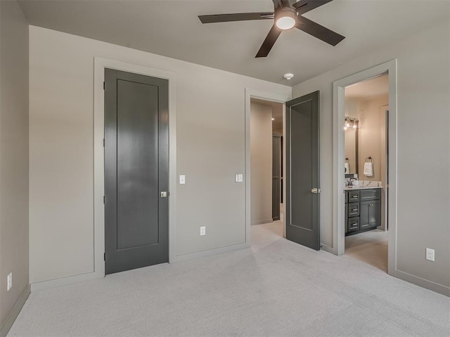 carpeted bedroom featuring ensuite bath, baseboards, ceiling fan, and a sink