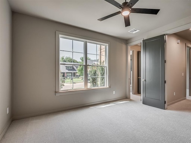 unfurnished bedroom with carpet floors, a ceiling fan, visible vents, and baseboards