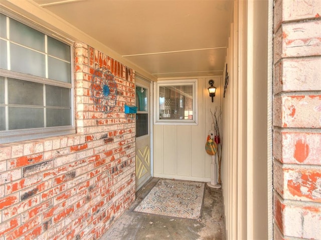 view of exterior entry with brick siding and a porch