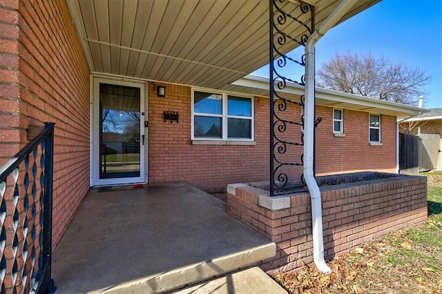 doorway to property with fence and brick siding