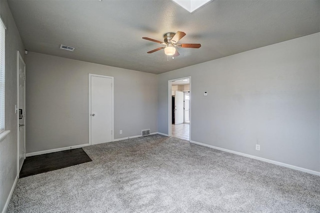 carpeted empty room with ceiling fan, a textured ceiling, and visible vents