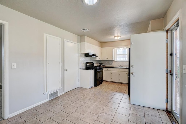 kitchen with dark countertops, visible vents, decorative backsplash, gas stove, and under cabinet range hood